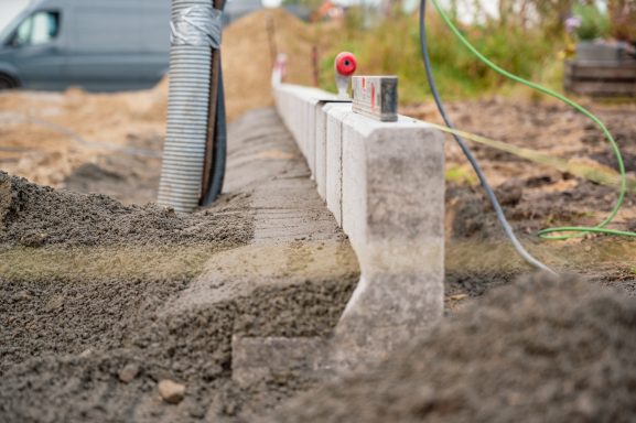 Betonfundament in einem Erdloch mit einem Messgerät in einem Baustellenumfeld.